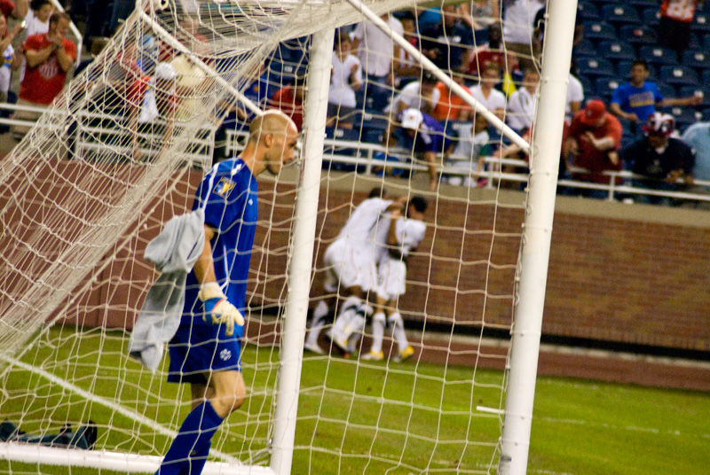 Canadian goalkeeper Lars Hirchfeld gathers his thoughts after giving up a bad first goal. The US players celebrate in the background. Canadian goalkeeper Lars Hirchfeld gathers his thoughts after giving up a bad first goal. The US players celebrate in the background.