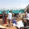 Mr. Tobias Lomuya (pointing at returnees offloading luggage) at the temporary campsite, Torit