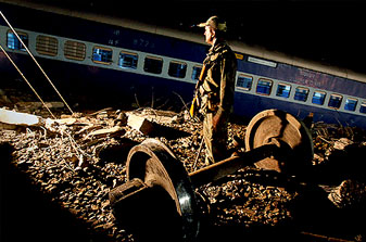 Security officer_stands_guard_next_to_a_derailed_passenger_train