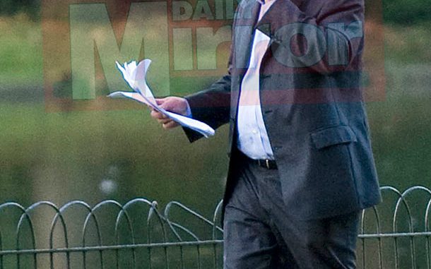 Oliver Letwin standing by a public bin while talking on mobile and having papers in one hand Oliver Letwin standing by a public bin while talking on mobile and having papers in one hand