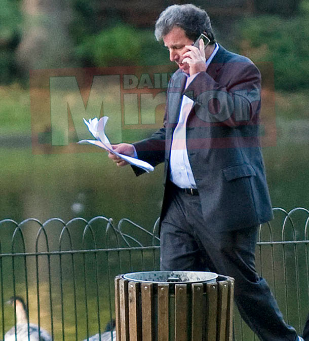 Oliver Letwin standing by a public bin while talking on mobile and having papers in one hand Oliver Letwin standing by a public bin while talking on mobile and having papers in one hand