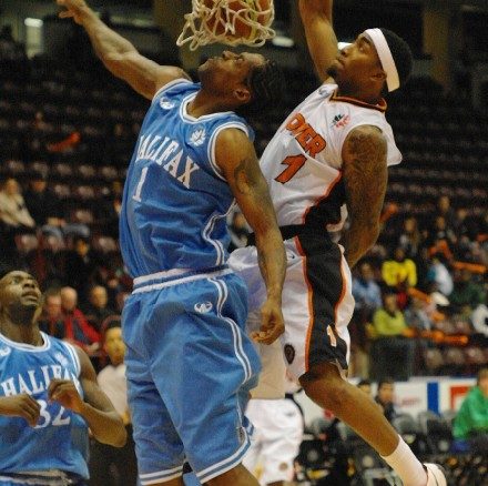 Oshawa Power small forward Marcus Johnson wins the battle of number 1's as he slams the ball down onto the face of former NBA player Eddie Robinson of the Halifax Rainmen.