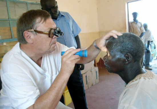 Dr. Sture Nyolme examining a patient's eyes as other patients wait to be attended to at Torit Hospital in Torit [©Gurtong]