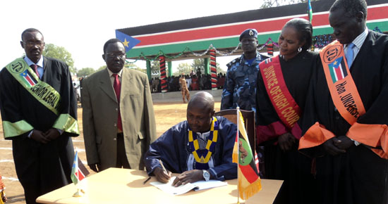 Governor Louis Lobong (centre) signing the constitution at Torit freedom square as the judiciary team witnessed [©Gurtong]