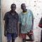 Mbini Brian Mbini (R) with the 2 suspects pose outside Bor police station holding cells [©Gurtong]