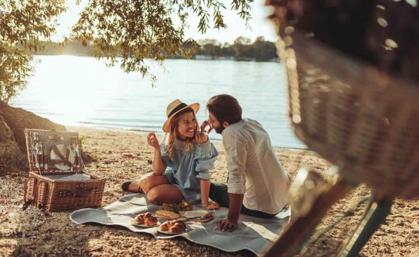 A young couple having a romantic picnic on a lake