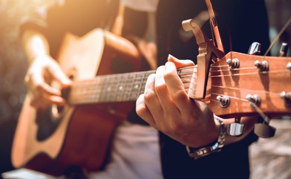 Closeup of man playing guitar with sunshine in the background