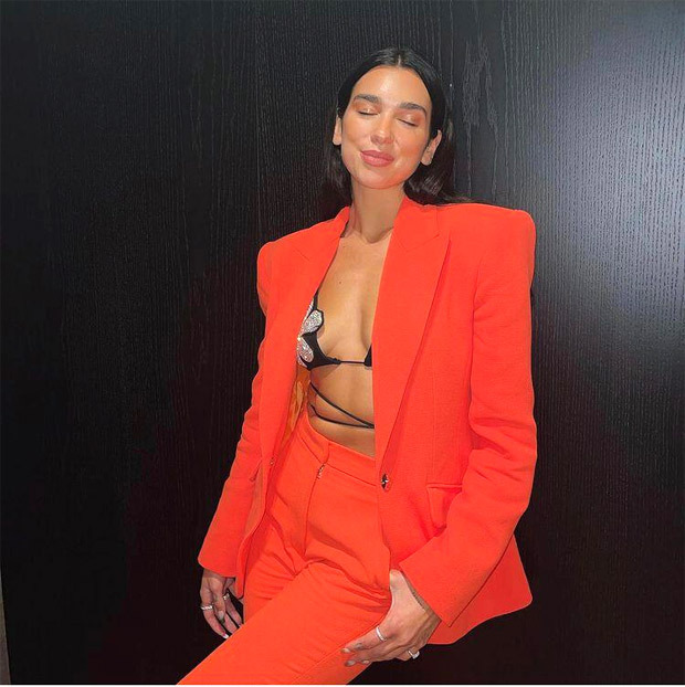 dua lipa makes a strong case for neon orange pantsuit paired with floss string bikini top